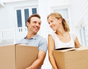 Happy mature man and woman with boxes moving in new house