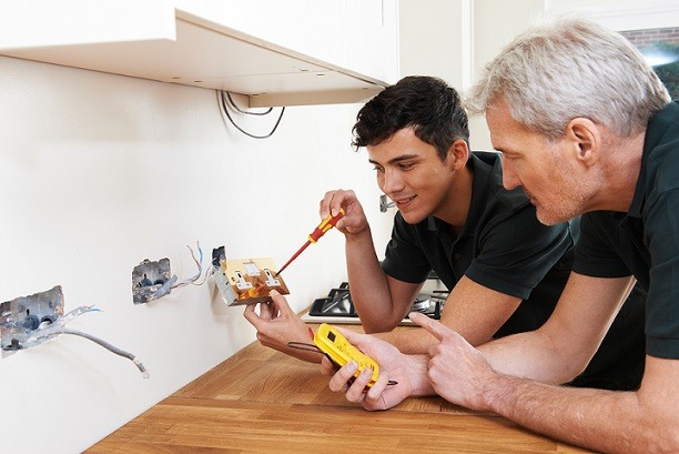 two men performing electrical duties in a wall