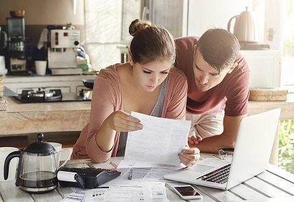 You can sell your home like this man and woman, reviewing the details of the sale on a piece of paper in their kitchen.