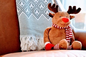 A couch with a scarf and reindeer stuff toy sitting