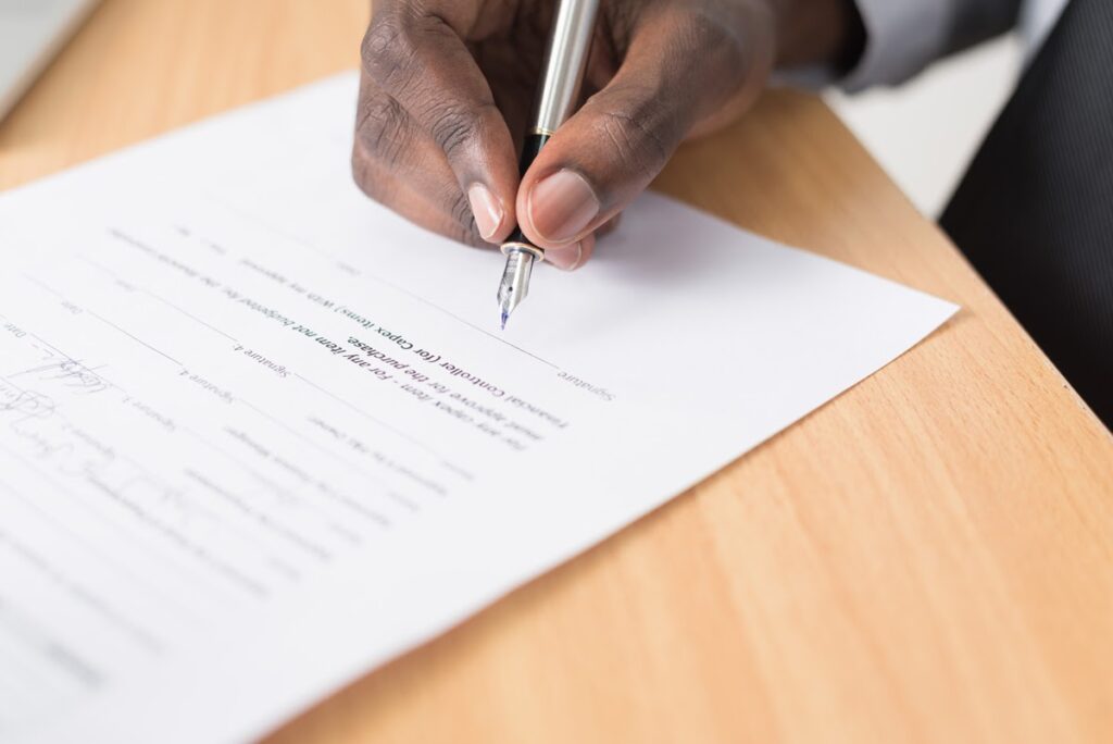 Man's hand hovering over home warranty document, ready to sign