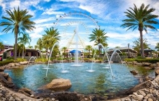 A decorative pond with palm trees and a ferris wheel behind